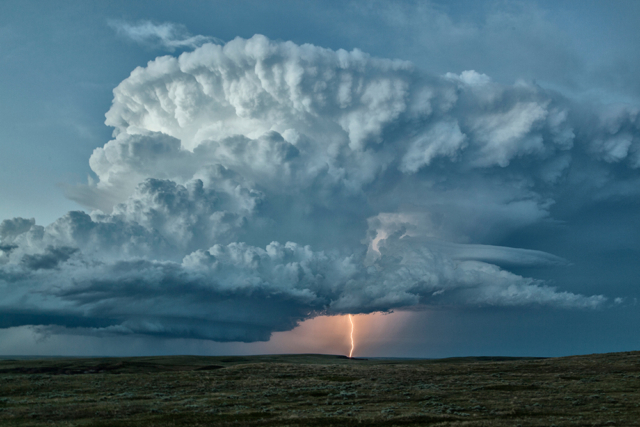 A massive supercell storm over a single lightning bolt.